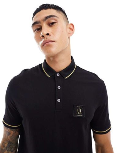 Polo nera in piqué con bordi a contrasto e logo dorato - Armani Exchange - Modalova