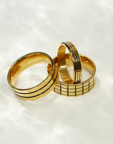 Confezione da 3 anelli a fascia dorati e neri in acciaio inossidabile resistente all'acqua con incisioni - ASOS DESIGN - Modalova