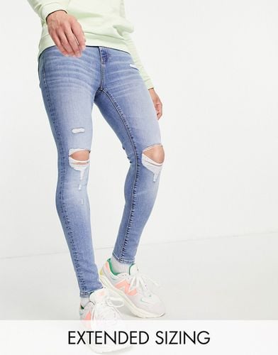Jeans spray on power stretch lavaggio medio con strappi sulle ginocchia e abrasioni - ASOS DESIGN - Modalova