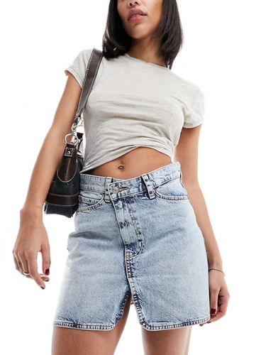 Minigonna di jeans lavaggio chiaro con incrocio in vita - ASOS DESIGN - Modalova