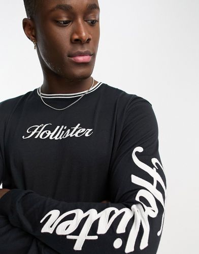 Maglia nera a maniche lunghe con logo sul davanti e sulle maniche con bordi - Hollister - Modalova