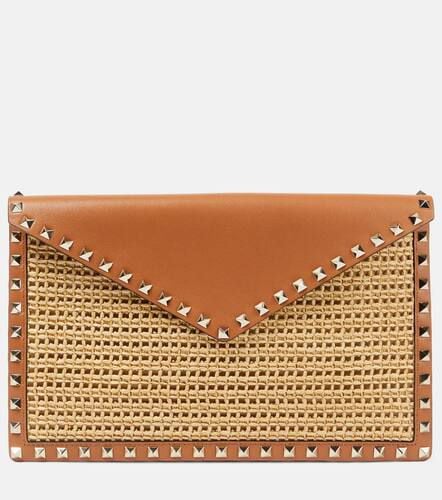 Rockstud Large leather-trimmed raffia clutch - Valentino Garavani - Modalova