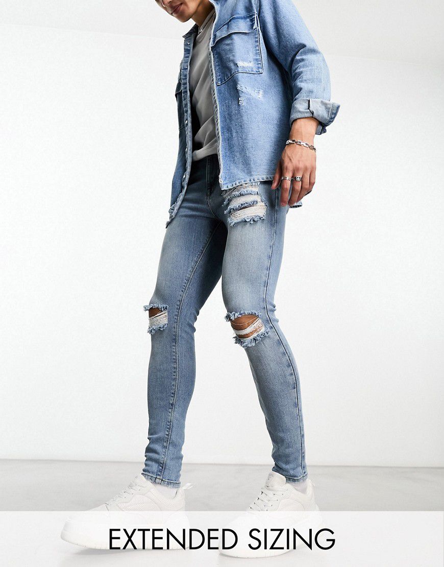 Jeans super elasticizzati lavaggio medio con strappi sulle ginocchia - ASOS DESIGN - Modalova